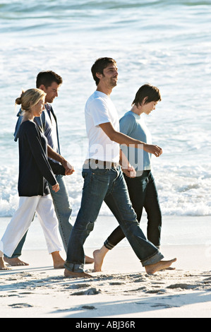 2 couples holding hands, walking on the beach Stock Photo