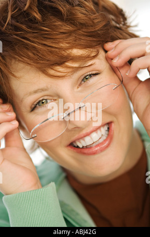 Portrait of young smiling woman putting her eye glasses on Stock Photo