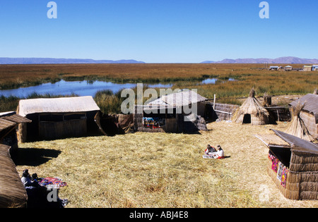 Lake Titicaca, Peru. Typical houses made of reeds on the floating island of Uros with women in traditional dress. Stock Photo