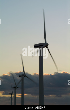 An image concerning energy of silhouetted windmills on an english coast shot at sunset with deep blue skies and some motion blur Stock Photo