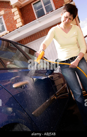 woman using hose pipe to clean car Stock Photo
