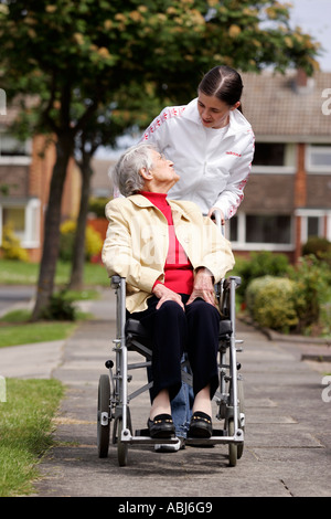 teenager helping old lady in wheel chair Stock Photo