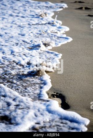 wave washing footsteps away clean sweep human existance Stock Photo