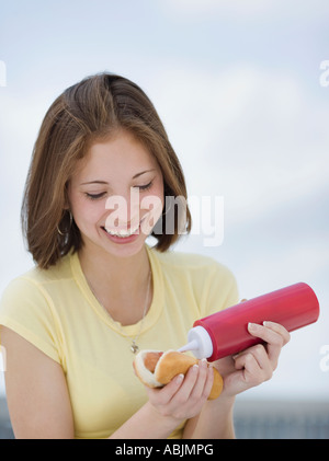 Woman putting ketchup on hotdog Stock Photo