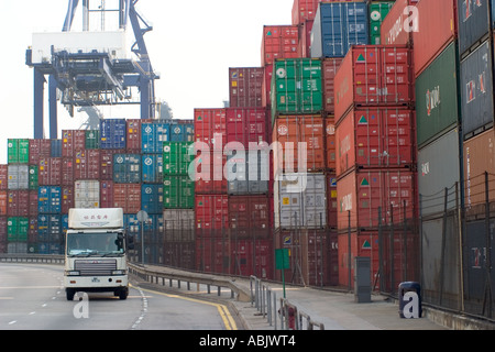 Large truck drives past container stacks with heavy lift crane in background container port Kwai Chung Stock Photo