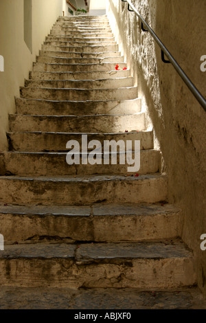 Narrow stone steps halfway up red flowers on the ground in the old part of the town Amalfi Italy Stock Photo