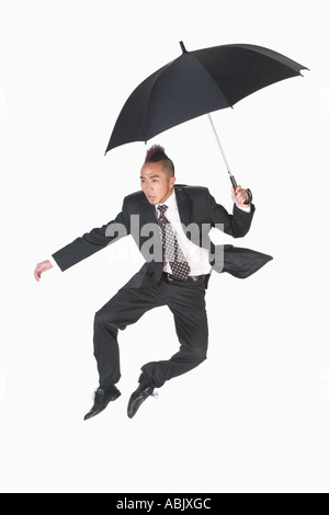 Hop skip jump Mary Poppins Punk with red Mohawk in Business suit with Umbrella perfect advertising shot for concept creative Stock Photo