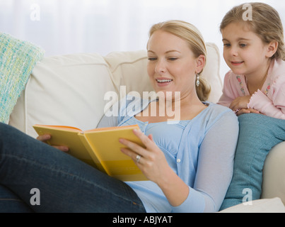 Mother reading to daughter on sofa Stock Photo