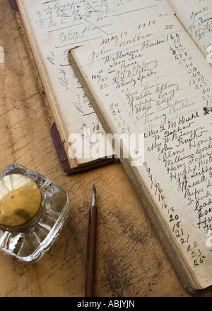 Quill pen and ink jar next to old ledger books Stock Photo