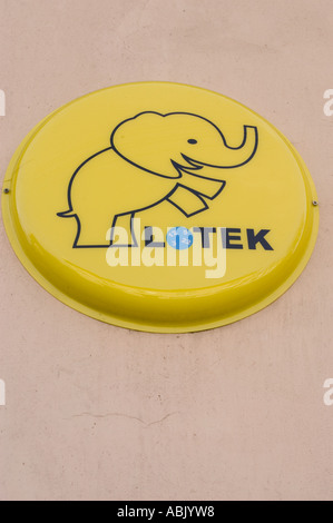 Yellow circular sign for the Polish lotto lottery Lotek, featuring a cartoon elephant symbol of luck, mounted on a wall in Poland. Stock Photo