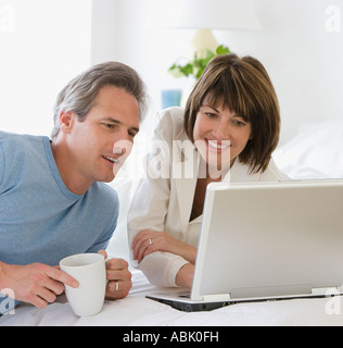 Couple looking at laptop on bed Stock Photo