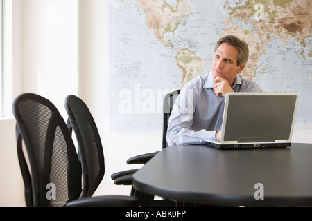Businessman thinking next to laptop Stock Photo