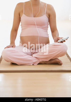 Pregnant woman sitting on yoga mat Stock Photo