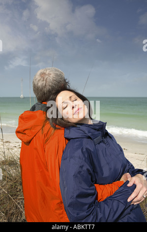 Photo of middle aged man and woman on the beach blanket wearing orange and navy blue windbreakers Stock Photo