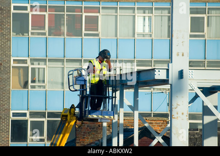 Welder working from a mobile access platform on a construction site in Manchester, England, UK Stock Photo