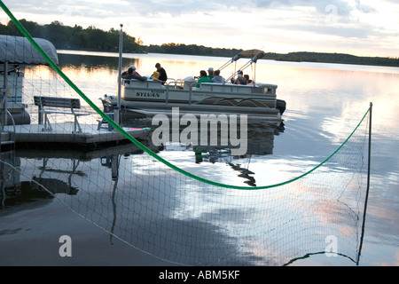 Family on an evening pontoon boat ride framed by water volleyball net. Kettle Moraine Lake Campbellsport Wisconsin WI USA Stock Photo