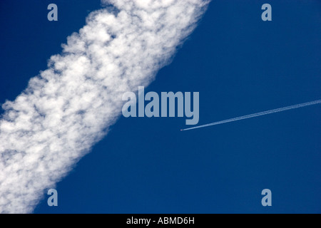 Vapor contrails from high flying jet aircraft The larger has been blown apart by the wind Stock Photo