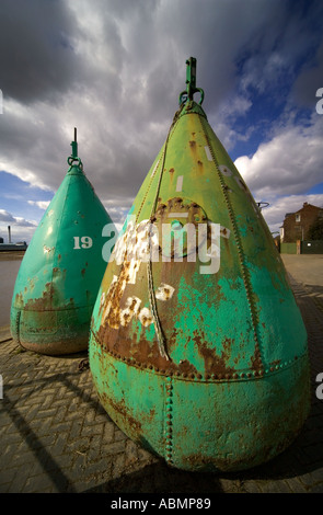 Large green buoys on the quay at Prufleet in King s Lynn in Norfolk England in March 2005 with dramatic skies Stock Photo