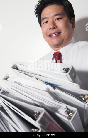 Businessman carrying stack of binders Stock Photo