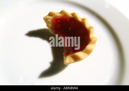 Jam tart on a white plate with a bite taken UK Stock Photo