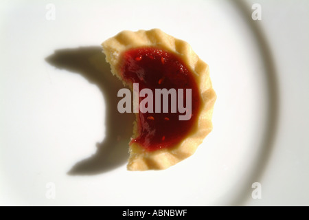 Jam tart on a white plate with a bite taken UK Stock Photo