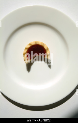 Jam tart on a white plate with a bite taken UK Stock Photo