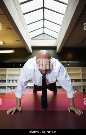 Businessman doing push-ups on conference table Stock Photo