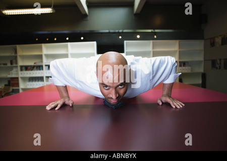 Businessman doing push-ups on conference table Stock Photo