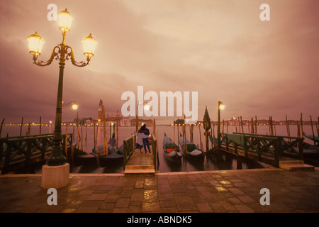 Couple embracing on waterfront near St Marks Square in Venice at dusk Stock Photo