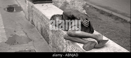 Many Cubans live in extreme poverty Homesless elderly woman asleep on a stone wall Havana Cuba Stock Photo