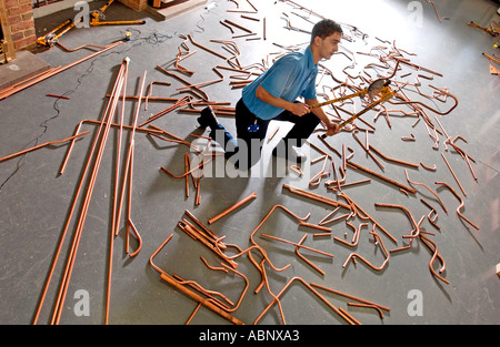 A young apprentice Gas Service Engineer practicing his skills with copper pipe benders Stock Photo
