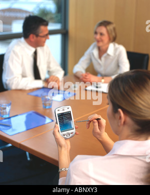 communicating via PDA during business meeting Stock Photo