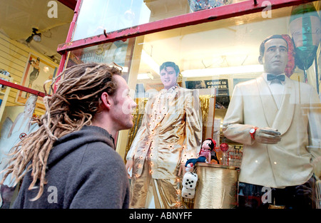 Dreadlocked young white man in grey hoodie looking at Bogart dummy in shop window Stock Photo