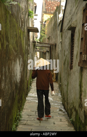 A woman walks down a narrow alleyway in Hoi An, Vietnam. Stock Photo