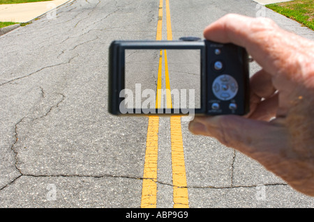 hand holding digital point and shoot camera showing yellow lines on road on camera LCD monitor Stock Photo