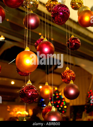 Multiple coloured glass baubles Christmas decorations hanging from ceiling Stock Photo