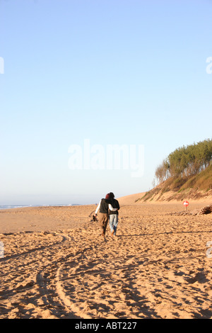 Young couple walking arm in arm on beach Stock Photo