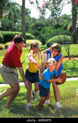 Young affluent family spending quality time together while playing football at a local park Stock Photo
