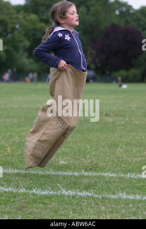 A girl jumps in the sack race at her school sports day, London junior school, Clissold park, Stoke newington, London, UK. Stock Photo