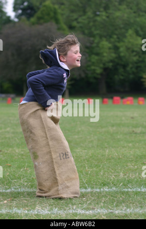 A girl jumps in the sack race at her school sports day, Clissold Park, London, UK. Sequence of 3 images. Stock Photo