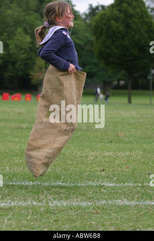 A girl jumps in the sack race at her school sports day, Clissold Park, London, UK. Sequence of 3 images. Stock Photo