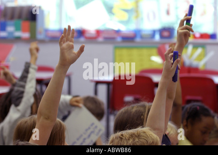 Children put their hands in the air during a lesson at a junior school,  Betty Layward school, London, UK. 2004. Stock Photo