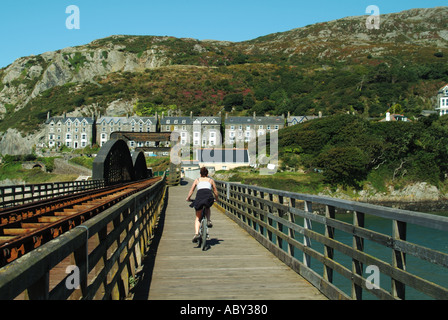 Afon Mawddach railway viaduct & footbridge for walking cycling link to Fairbourne side of estuary bike rider pedalling towards Barmouth North Wales UK Stock Photo