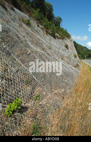roadside cliff covered in wire netting to help contain rock debris ...