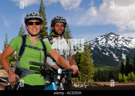 Smiling mountain bikers near snow capped Mount Bachelor Oregon USA Stock Photo