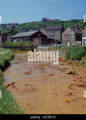 River pollution from iron oxide polluted ground water seeping from old ironstone mine, Skinningrove, Cleveland, England, UK. Stock Photo