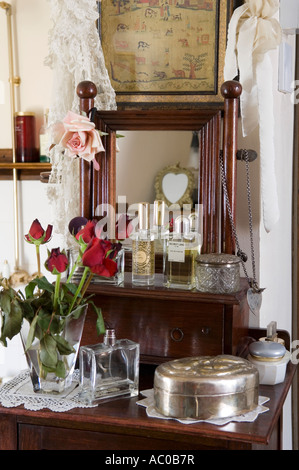 Red roses on dressing table with old perfume bottles Stock Photo