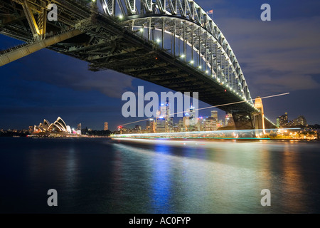 Light trails from a passing ferry are framed by the Sydney Opera House and Harbour Bridge at Milsons Point Stock Photo