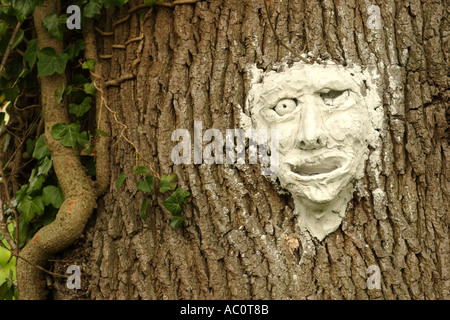 Mask made from clay and attached to trunk of ancient oak tree Stock Photo