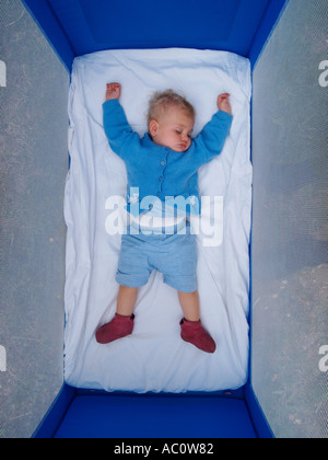 Little girl 11 months old exhausted and sleeping outdoors in a foldable bed on a camping site Haute Marne France Stock Photo